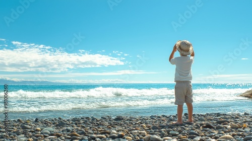 Young Boy Silhouetted on Rocky Coastal Shoreline with Serene Ocean Horizon photo