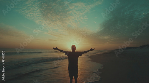 Man with arms outstretched standing on the seashore at sunset. photo