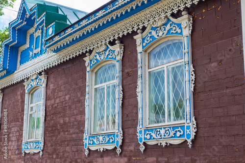 Row of windows with carved frames on old wooden house in Biysk town at Altai Krai, Russia. Russian folk style in architecture. Fragment of the facade of an old historic wooden house photo