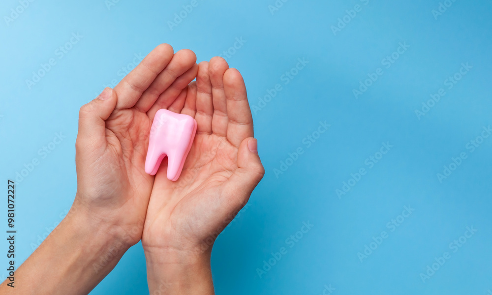 A hand holding a big tooth on a blue background. Concept of dental care. Teeth Clean and Oral Health. Taking care of yourself. Taking care of health. Close-up. Place for text.
