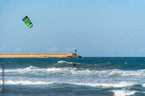 A young man kitesurfing at sunset in the sea.