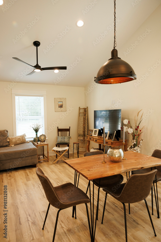 Modern living room with a wooden dining table, black chairs, and pendant lighting complemented by a cozy sofa and television set, Florida, USA Modern living room with a wooden dining table, black chairs, and pendant lighting complemented by a cozy sofa and television set, Florida, USA