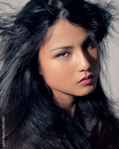 Close-up portrait of a woman with flowing dark hair and intense gaze. photo