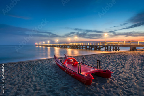 Fototapeta Naklejka Na Ścianę i Meble -  The pier of Forte dei Marmi and a lifeguard rowing catamaran at sunset. Versilia, Tuscany, Italy