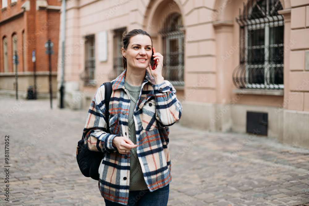 Beautiful stylish woman in trendy wear spending time on street using smartphone. Happy girl with backpack talking on the mobile phone. Urban lifestyle concept Beautiful stylish woman in trendy wear spending time on street using smartphone. Happy girl with backpack talking on the mobile phone. Urban lifestyle concept
