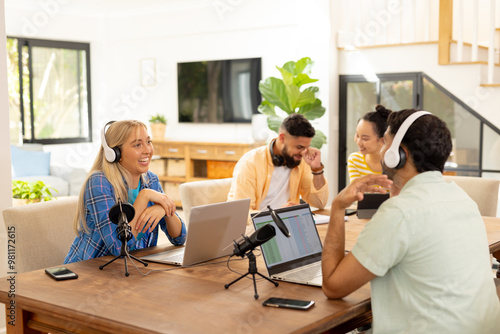 Recording podcast, group of young friends using laptops and microphones indoors