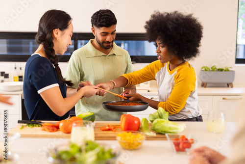 Cooking together, young diverse friends preparing meal in modern kitchen, enjoying time