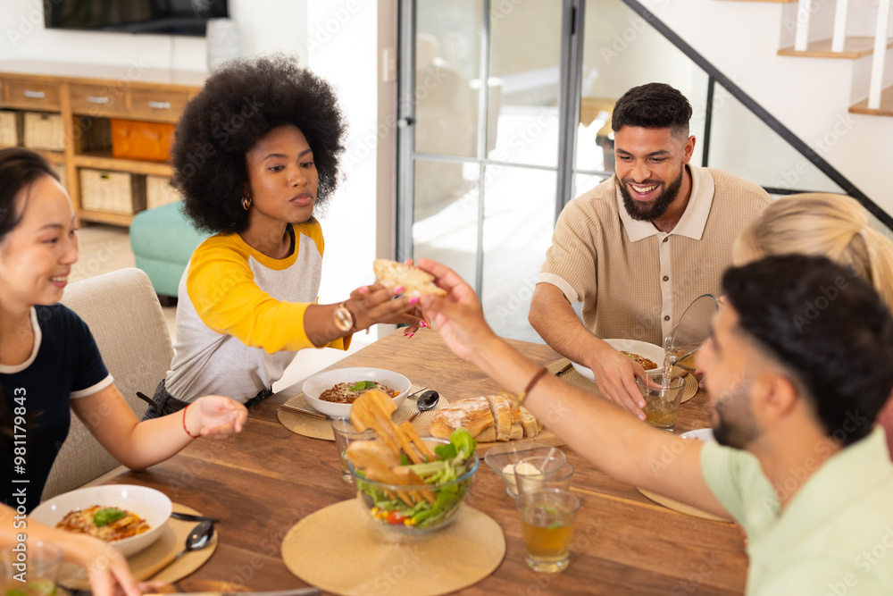 Sharing food and enjoying meal, young diverse friends gathering around dining table Sharing food and enjoying meal, young diverse friends gathering around dining table