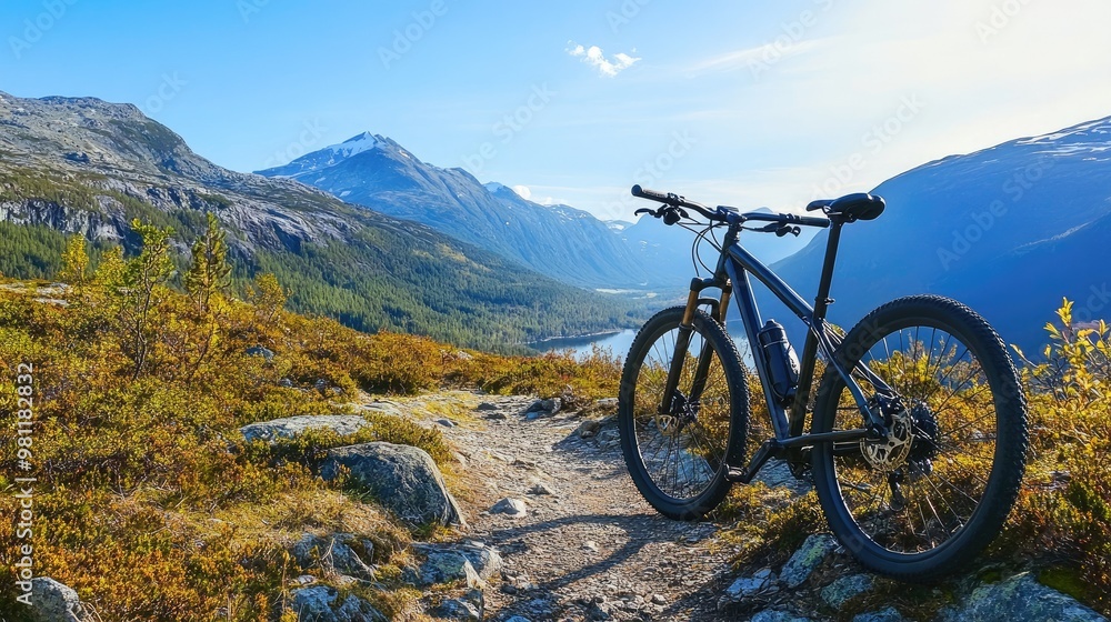 A mountain bike resting against a rocky trail, with the background of a scenic mountain landscape and clear blue sky. A mountain bike resting against a rocky trail, with the background of a scenic mountain landscape and clear blue sky.