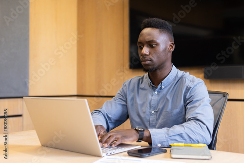 Working on laptop, man in office focusing on business tasks, copy space