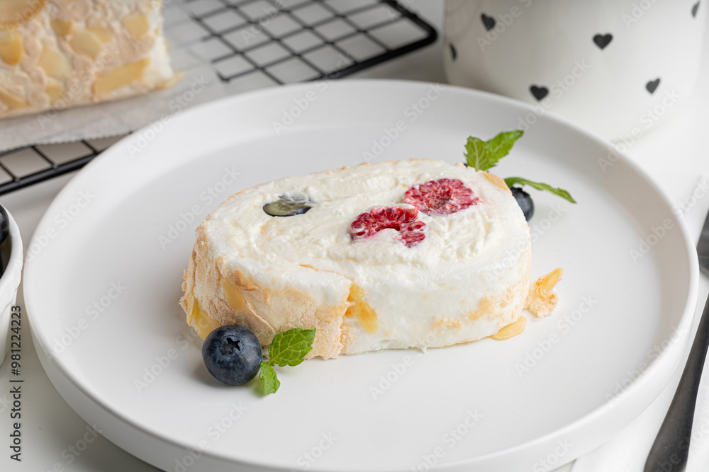 meringue roll with raspberries and blueberries on a white plate