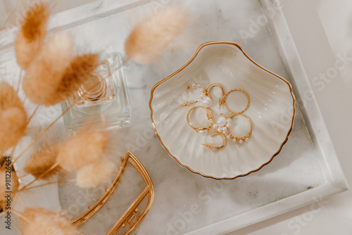 Εκτύπωση καμβά Golden jewelry on ceramic tray closeup, feminine dressing table with organizer and sunlight shadows