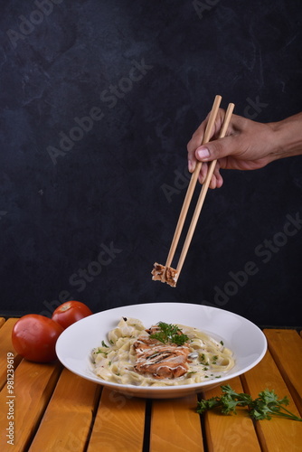 Fettuccine Alfredo with chicken served in a bowl, captured from an angle view. The creamy sauce and pasta create an appealing presentation for a restaurant setting. photo