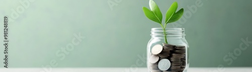 A small jar filled with coins and a green plant sprouting from the top, symbolizing growth and investment. photo