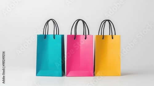 Colorful shopping bags in turquoise, pink, and yellow, arranged side by side against a white background, perfect for gifts and retail displays.