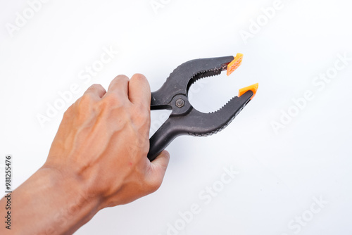 Foto A man's hand is holding a black and orange plastic clamp (screen clamp) on a pla
