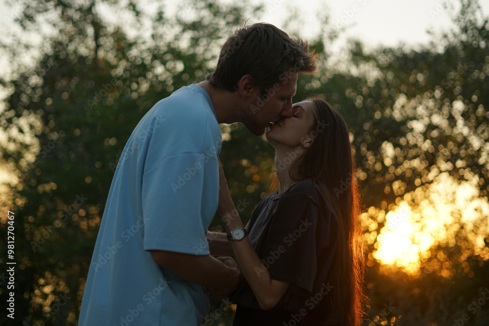 man and woman stand close to each other in a forest during sunset, the sun shining brightly behind the trees man and woman stand close to each other in a forest during sunset, the sun shining brightly behind the trees