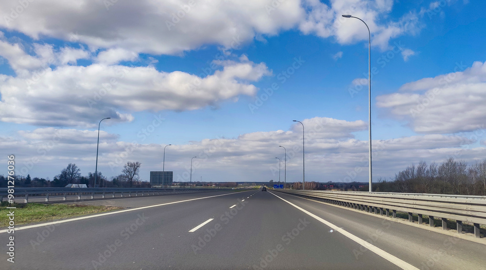 A tranquil highway scene with clear blue skies and fluffy clouds, perfect for travel and adventure themes. A tranquil highway scene with clear blue skies and fluffy clouds, perfect for travel and adventure themes.