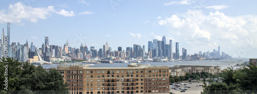 view of midtown manhattan skyline from a public park in west new york (city in jersey, nj, nyc) green space urban living hudson river blue sky clouds skyscraper cityscape high rise