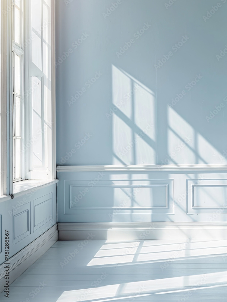 Obraz premium A serene and bright empty room with soft blue walls and gentle sunlight casting shadows through large windows creates peaceful atmosphere