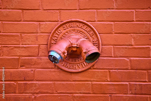 Orange Fire Department Connection on Brick Wall Close-Up photo