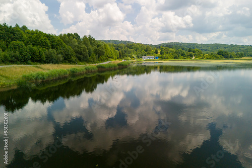 A serene landscape featuring a tranquil lake surrounded by lush greenery and a reflection of clouds