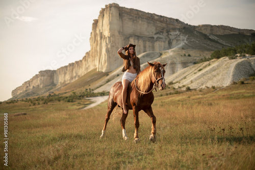 Shot of a beautiful young woman riding a horse. A young girl with long hair in a swimsuit rides a horse at sunset on a ranch in the mountains