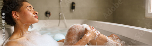 A woman is enjoying a bath in a foamy tub filled with water in the bathroom