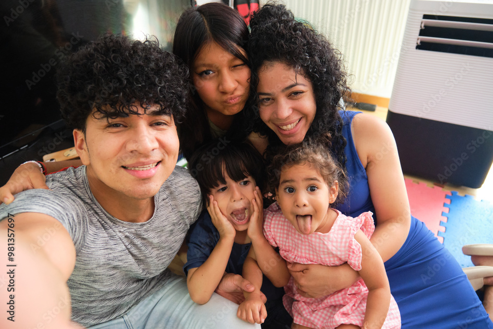 Happy latin family is making funny faces while taking a selfie at home