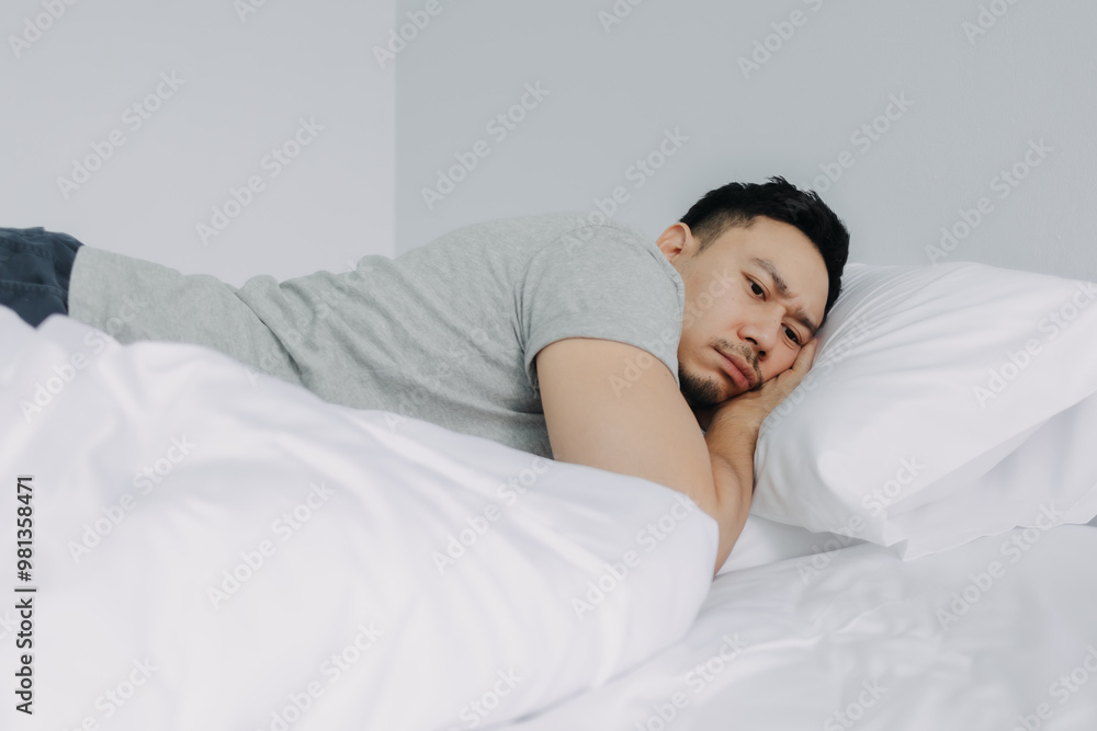 Serious and depressed asian man overthinking the problems lying on the bed. Serious and depressed asian man overthinking the problems lying on the bed.