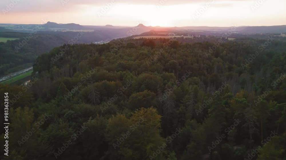 Sunset view over the dense forest and distant mountains from a rocky viewpoint in Schrammsteine Elbe Sandstone Mountains Germany Sunset view over the dense forest and distant mountains from a rocky viewpoint in Schrammsteine Elbe Sandstone Mountains Germany