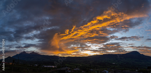 Spectacular Andean sunset with the silhouette of the Ilinizas and Corazon volcanoes under reddish and gray clouds.