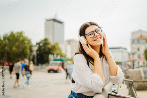 Young caucasian woman listening to music or audio book in the city