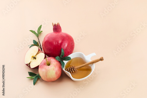 Rosh Hashanah. Rosh Hashanah featuring a honey, pomegranate, and apple on a beige background. photo