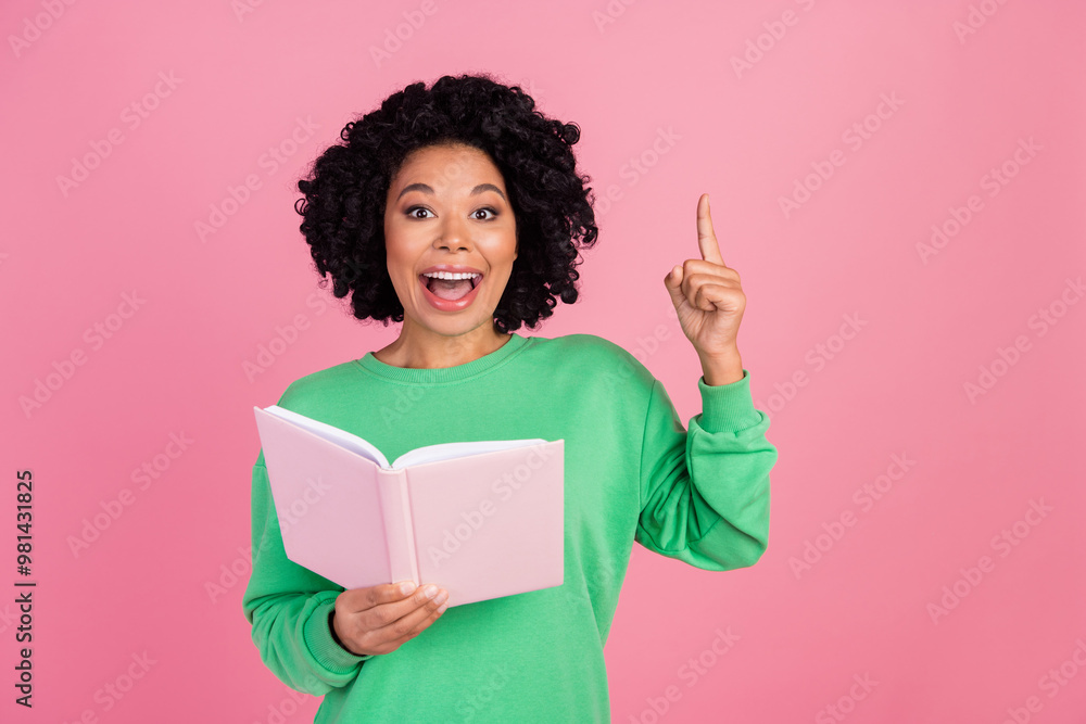 Photo of smart lady with curly black hairstyle holding book to prepare for exam point finger up eureka isolated on pink color background Photo of smart lady with curly black hairstyle holding book to prepare for exam point finger up eureka isolated on pink color background