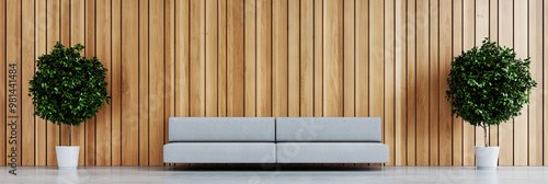 A gray sofa sits in front of a wood-paneled wall with two potted plants.