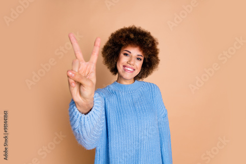 Photo of positive cheerful girl with chevelure dressed blue knit sweater showing v-sign symbol to you isolated on pastel color background