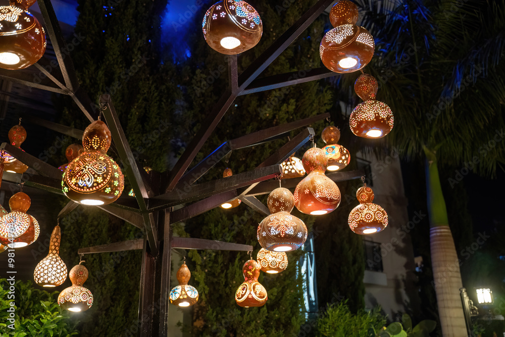A string of colorful, handcrafted gourd lanterns illuminated at night, creating a beautiful and festive atmosphere.