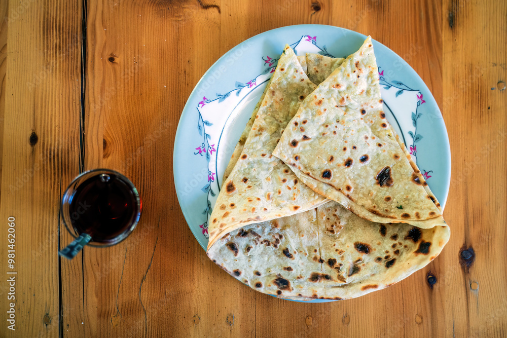 A plate of delicious Turkish gozleme, a savory pastry filled with cheese, spinach, or potatoes, served with a glass of Turkish tea