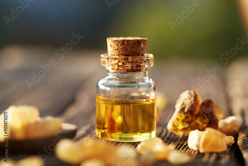 A bottle of frankincense essential oil with boswellia resin on a table outdoors