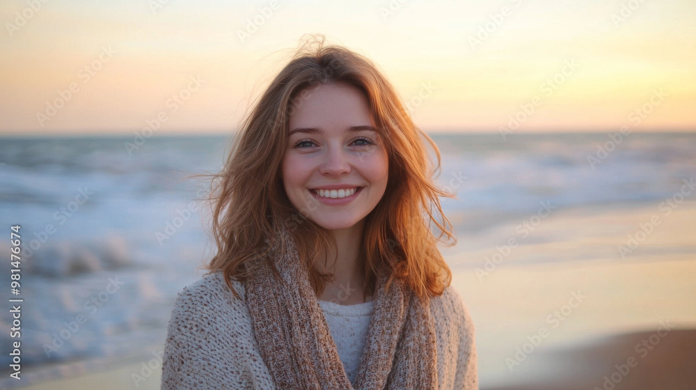 Smiling young woman standing on a windy beach at sunset, soft golden light and peaceful waves Smiling young woman standing on a windy beach at sunset, soft golden light and peaceful waves