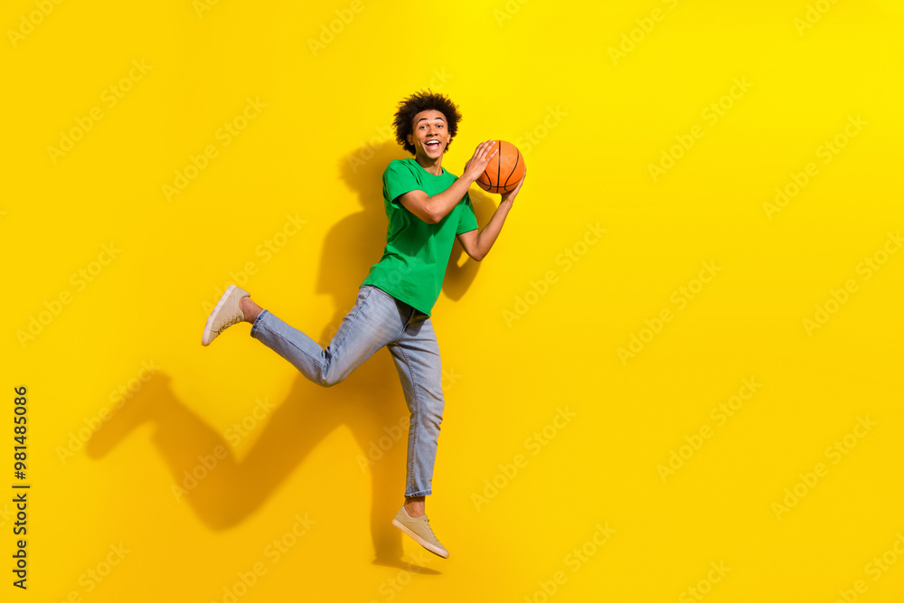 Full length photo of attractive funny guy wear green t-shirt jumping high enjoy basketball emtpy space isolated yellow color background Full length photo of attractive funny guy wear green t-shirt jumping high enjoy basketball emtpy space isolated yellow color background