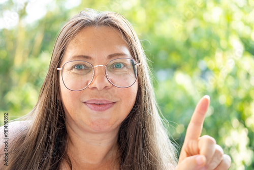 Wallpaper Mural close-up stylish mature woman wearing glasses, smiling confidently and pointing towards something, positivity and enthusiasm Torontodigital.ca