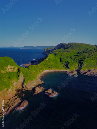 A Serene Coastal Landscape Features Lush Green Hills Alongside Calm Waters, Perfect for Reflection