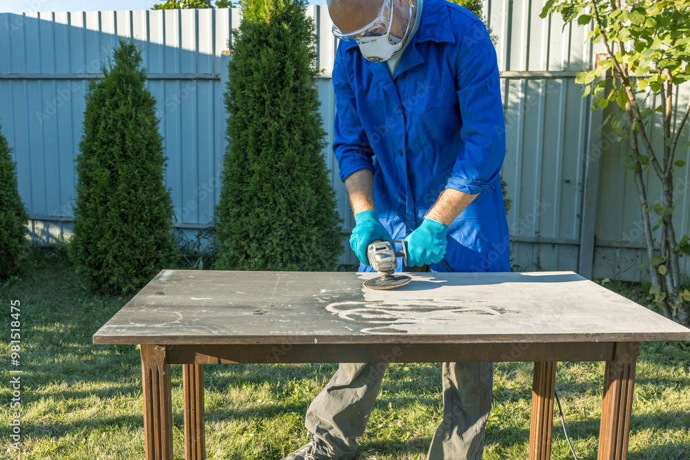 A man in a blue shirt is working on a table with a power tool A man in a blue shirt is working on a table with a power tool