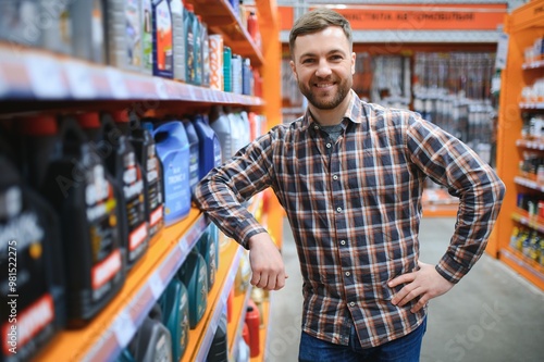 seller man with canister of motor oil in auto store photo