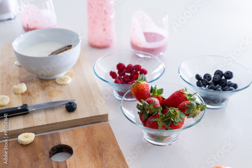 At home, Preparing healthy smoothie, fresh strawberries, blueberries, and raspberries in bowls photo