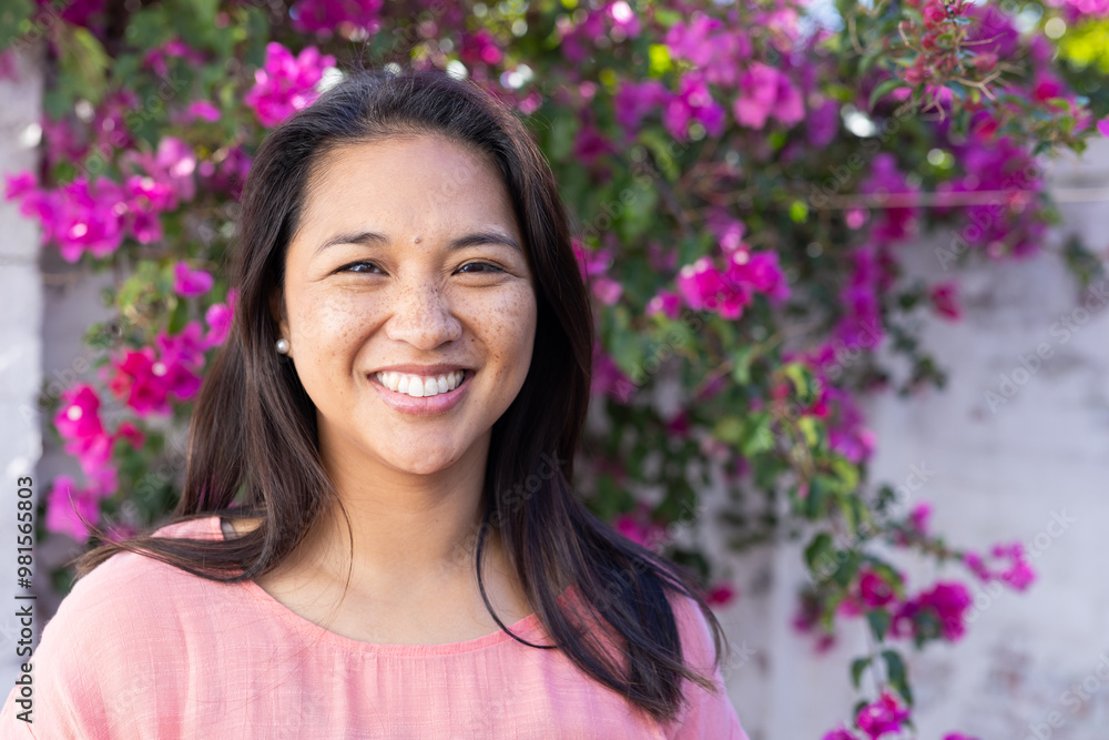Standing in garden with blooming pink flowers, smiling woman enjoying outdoor lifestyle Standing in garden with blooming pink flowers, smiling woman enjoying outdoor lifestyle
