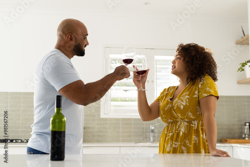 Toasting with wine glasses, couple enjoying time together in modern kitchen photo