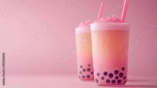 Two pink Boba tea drinks with straws in them